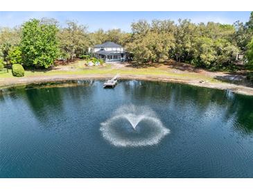 Expansive property features a private lake with fountain, lush landscaping, and a charming home with screened porch at 835 Dyson Dr, Winter Springs, FL 32708