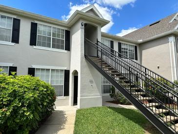 Attractive condo exterior with black shutters, green grass, and black railing up the stairs at 9021 Lee Vista Blvd # 1707, Orlando, FL 32829