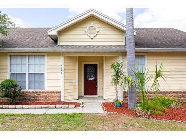 Charming home featuring a brick facade, well-manicured landscaping, and a striking red front door at 321 Moffat Loop, Oviedo, FL 32765