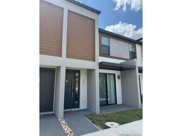 Modern townhome with neutral tones, wooden accents, and stylish front door at 3296 Tranquil Trl, Kissimmee, FL 34747