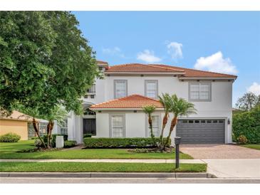 Stately two-story home with tile roof, brick driveway, manicured lawn and a gray two-car garage at 2107 Rickover Pl, Winter Garden, FL 34787