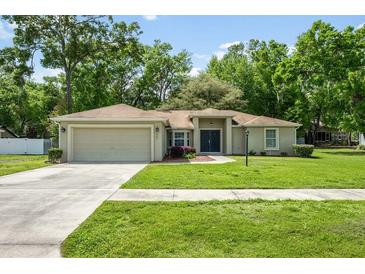 Charming single-story home with well-manicured lawn, mature trees, and a two-car garage at 304 Woods Landing Dr, Lady Lake, FL 32159