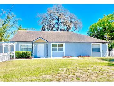 Charming single story home featuring a well manicured lawn and a white picket fence at 307 S Hiawassee Rd, Orlando, FL 32835