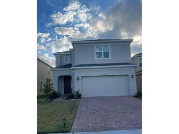 Charming two-story home with a brick driveway, attached two-car garage, and well-manicured lawn at 5014 Royal Point Ave, Kissimmee, FL 34746