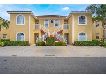 Attractive two-story condo with a yellow exterior, red tile roof, white stair railings, and well-maintained landscaping at 5201 Lake Marion Golf Resort # 5201, Kissimmee, FL 34759