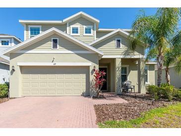 Charming two-story home with a well-manicured front yard, brick walkway, and a two-car garage at 609 Fortuna Dr, Davenport, FL 33837