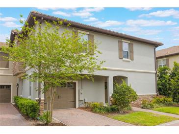 Two story house with a two car garage and an arched entryway surrounded by lush landscaping at 1312 Shinnecock Hills Dr, Davenport, FL 33896