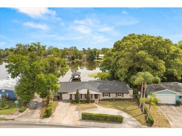 Lakefront home showcases stylish gray brick, mature landscaping, and a private dock for waterfront enjoyment at 201 Cedarwood Dr, Maitland, FL 32751