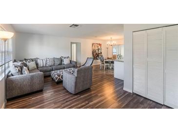 Bright living room with modern gray furnishings and stylish dark wood laminate flooring flowing to the dining area at 2070 Keyes Ln, Deltona, FL 32738