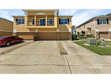 Three-story townhome featuring an attached garage and well-manicured landscaping and a red car out front at 2124 Betsy Ross Ln, St Cloud, FL 34769