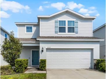Charming two-story home featuring a two-car garage and a welcoming light-blue front door at 2237 Wood Stork Ln, St Cloud, FL 34771
