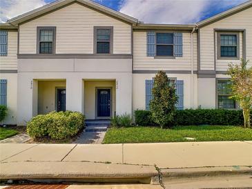 Charming townhome featuring a manicured lawn and neutral siding with blue shutters in a well-maintained community at 2412 Tanger Dr, Kissimmee, FL 34747