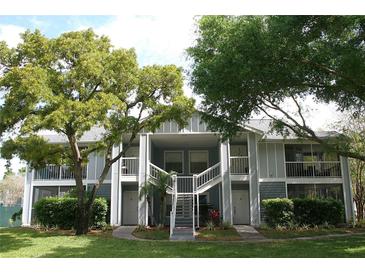 Two-story condo building featuring a staircase, balconies, neutral paint, and mature trees at 2593 Grassy Point Dr # 101, Lake Mary, FL 32746