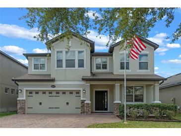 Two-story home showcasing a brick driveway, a well-manicured lawn, and a charming two-car garage at 5144 Ravena E Ave, St Cloud, FL 34771