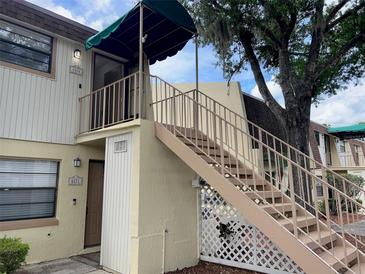 Exterior view of a two-story condominium building featuring private entry with stairs and green awning to block sun at 6104 Topher Trl # 6104, Mulberry, FL 33860