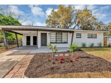 Charming single-story home featuring a covered carport and freshly landscaped front yard with flowers at 6312 Appian Way, Orlando, FL 32807