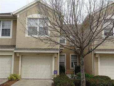 Exterior view of a tan two-story townhome with an attached single car garage at 6453 Alcalde Ct # 104, Orlando, FL 32835