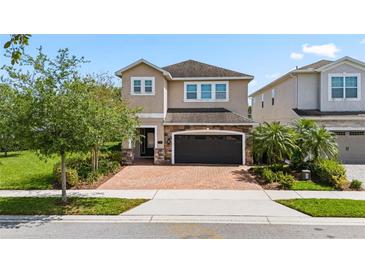 Charming two-story home featuring a brick driveway, a two-car garage, and beautiful landscaping at 7392 Marker Ave, Kissimmee, FL 34747