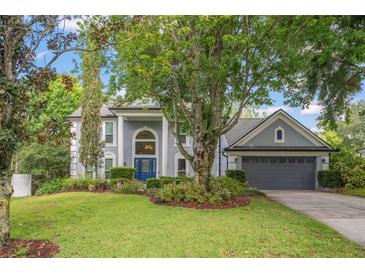 Charming two-story home with a lush front lawn, mature trees, and a neatly manicured landscape at 1311 Olympia Park Cir, Ocoee, FL 34761