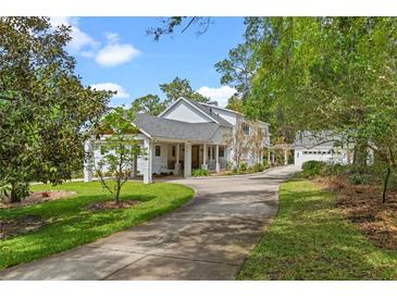 Stunning exterior of home featuring a covered portico, long driveway, and mature trees at 1417 Olympia Ave, Mount Dora, FL 32757