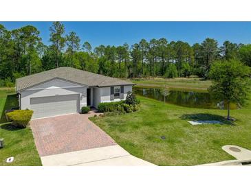 Charming single-story home with a well-manicured lawn, pond view, and brick driveway at 17309 Cagan Crossing Blvd, Clermont, FL 34714