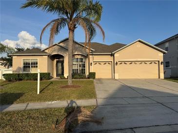 Charming single-story home with a three car garage, well-manicured lawn, and a mature palm tree in the front yard at 2715 Bartlet Dr, Kissimmee, FL 34741