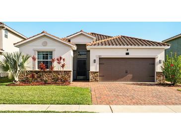 Charming single-Gathering home featuring a tile roof, brick driveway, and well-manicured landscaping at 3053 Brook Stone Ter, Davenport, FL 33837