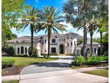 Stately two-story home with lush landscaping and a circular driveway lined with towering palm trees at 6137 Grosvenor Shore Dr, Windermere, FL 34786