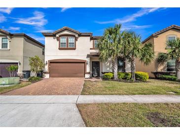 Two-story home boasts a lush, landscaped front yard and a brick-paved driveway leading to a two-car garage at 8840 Bengal Ct, Kissimmee, FL 34747