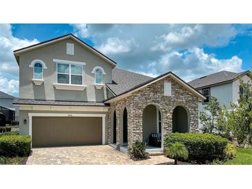 Charming home featuring a stone archway, two-car garage, and neatly landscaped yard at 9004 Sunshine Ridge Loop, Kissimmee, FL 34747