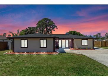 Charming single-story home with well-manicured lawn and inviting entrance, enhanced by colorful sunset backdrop at 5828 Westport Dr, Port Orange, FL 32127