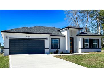 Beautiful single Gathering home with a white exterior, gray accents, well-manicured lawn, and a two car garage at 16358 Sw 27Th Terrace Rd, Ocala, FL 34473