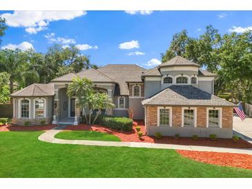 Beautiful two-story home with a well-manicured lawn, red mulch, and mature trees at 205 Torcaso Ct, Winter Springs, FL 32708
