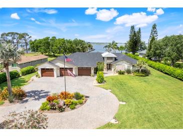 Stunning waterfront home featuring a three-car garage, circular driveway, lush landscaping, and picturesque water views at 3640 Crump Rd, Winter Haven, FL 33881