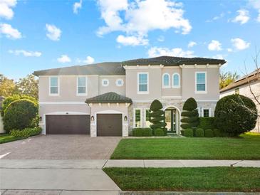 Elegant two-story home with a manicured lawn, a three-car garage, and a stone-accented facade at 645 American Holly Pl, Oviedo, FL 32765