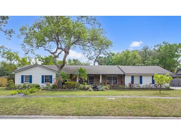 Charming single-story home with lush landscaping, mature trees, and blue shutters at 801 Fox Valley Dr, Longwood, FL 32779