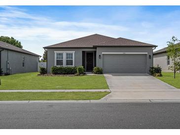 Charming one-story home with a well-manicured lawn, gray exterior, and attached two-car garage at 1030 Alabaster Way, Deltona, FL 32725