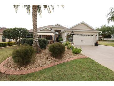 Charming single-story home featuring a lush landscaped yard, complemented by a cozy front porch and a two-car garage at 1669 Plum Branch Ter, The Villages, FL 32162