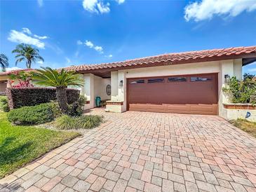 Charming home exterior with a paver driveway, well-manicured landscaping, and a two-car garage at 7808 The Esplanade Ct, Orlando, FL 32836
