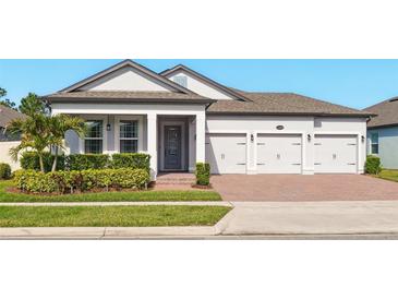 Well-maintained single-Gathering home with a three-car garage and manicured lawn at 13202 Spring Grove Way, Winter Garden, FL 34787