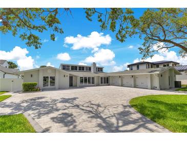 Expansive front yard with a stunning modern home featuring a three-car garage and beautiful landscaping at 49 Interlaken Rd, Orlando, FL 32804