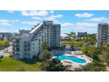 Condo exterior featuring a pool, nearby businesses, well-maintained landscaping and clear blue skies at 6165 Carrier Dr # 2001, Orlando, FL 32819