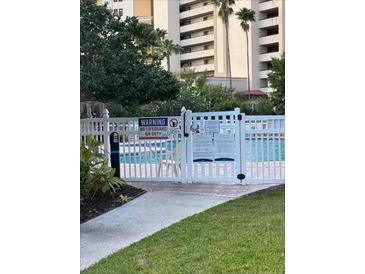 Community pool with white picket fence, warning signs, and views of the building and palm trees at 6165 Carrier Dr # 3104, Orlando, FL 32819