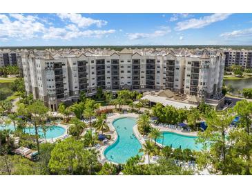 A beautiful aerial view of the resort-style pools surrounded by lush landscaping and multi-story condo buildings at 14501 Grove Resort Ave # 3735, Winter Garden, FL 34787