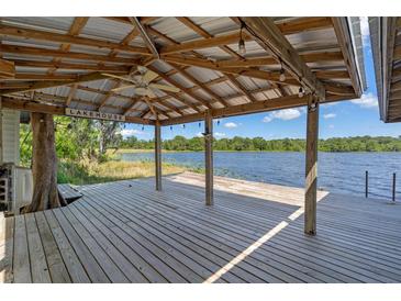 Lake house deck with a metal roof covering, ceiling fan, views of the lake, and wooden beams at 18618 Lake Pickett Rd, Orlando, FL 32820