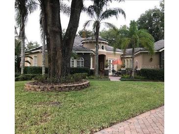 Stucco home with a barrel tile roof, mature landscaping, and a charming patio with an orange umbrella at 2108 Northumbria Dr, Sanford, FL 32771