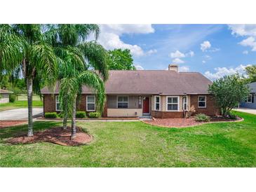 Charming single-story home featuring a lush green lawn and mature palm trees at 2621 Ardon Ave, Orlando, FL 32833