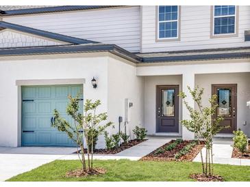 Charming townhome with a light blue garage door, manicured lawn and welcoming entrance at 914 Poppy Ln, Dundee, FL 33838