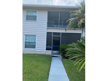 Exterior shot featuring a two-story condo with neutral siding, a screen door, and a landscaped lawn at 1001 Plantation Dr # A2, Kissimmee, FL 34741