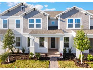 Charming townhome featuring a manicured lawn, gray siding, and inviting covered entry at 13540 Autumn Harvest Ave, Winter Garden, FL 34787